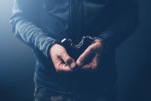 Arrested computer hacker with handcuffs